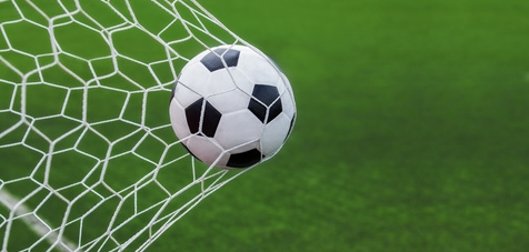 soccer ball in goal with green backgroung