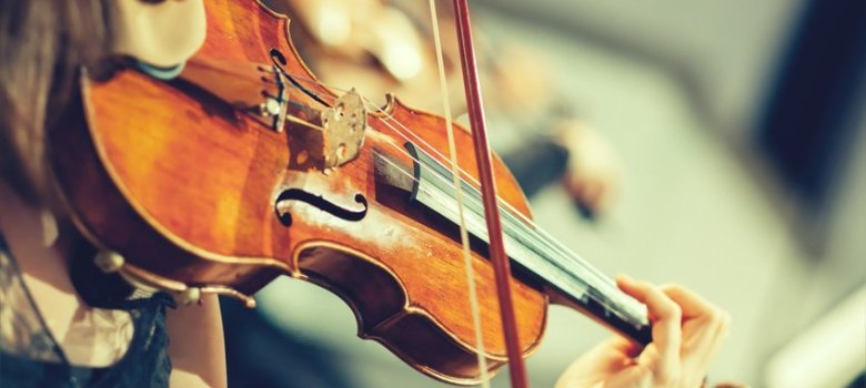 Symphony orchestra on stage, hands playing violin