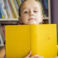 kleines mädchen umarmt einen buch in der bücherei.lesen lernen.