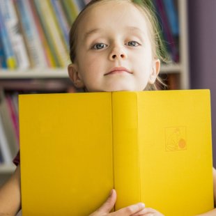 kleines mädchen umarmt einen buch in der bücherei.lesen lernen.