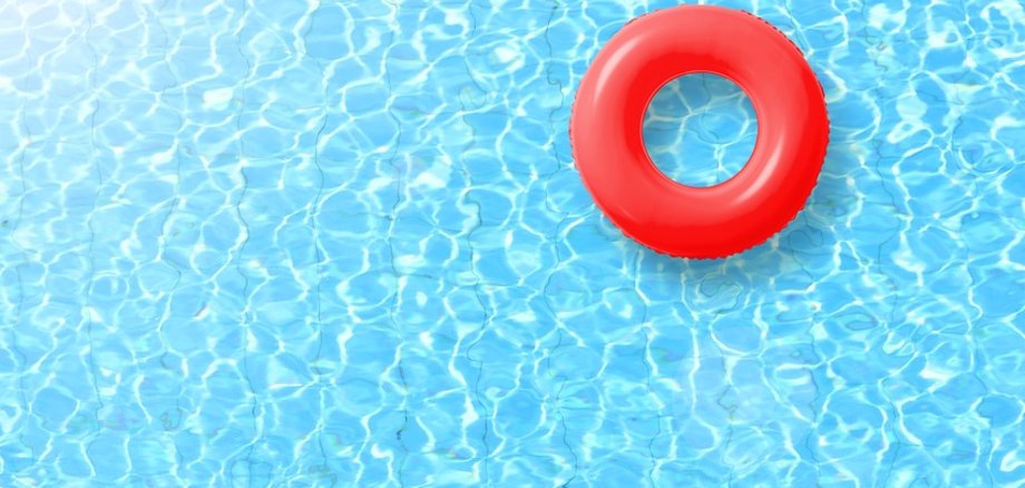 red swimming pool ring float in blue water and sun bright. concept color summer.