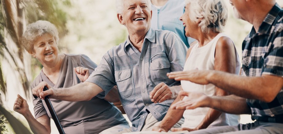 Happy elderly man with walking stick and smiling senior people relaxing in the garden