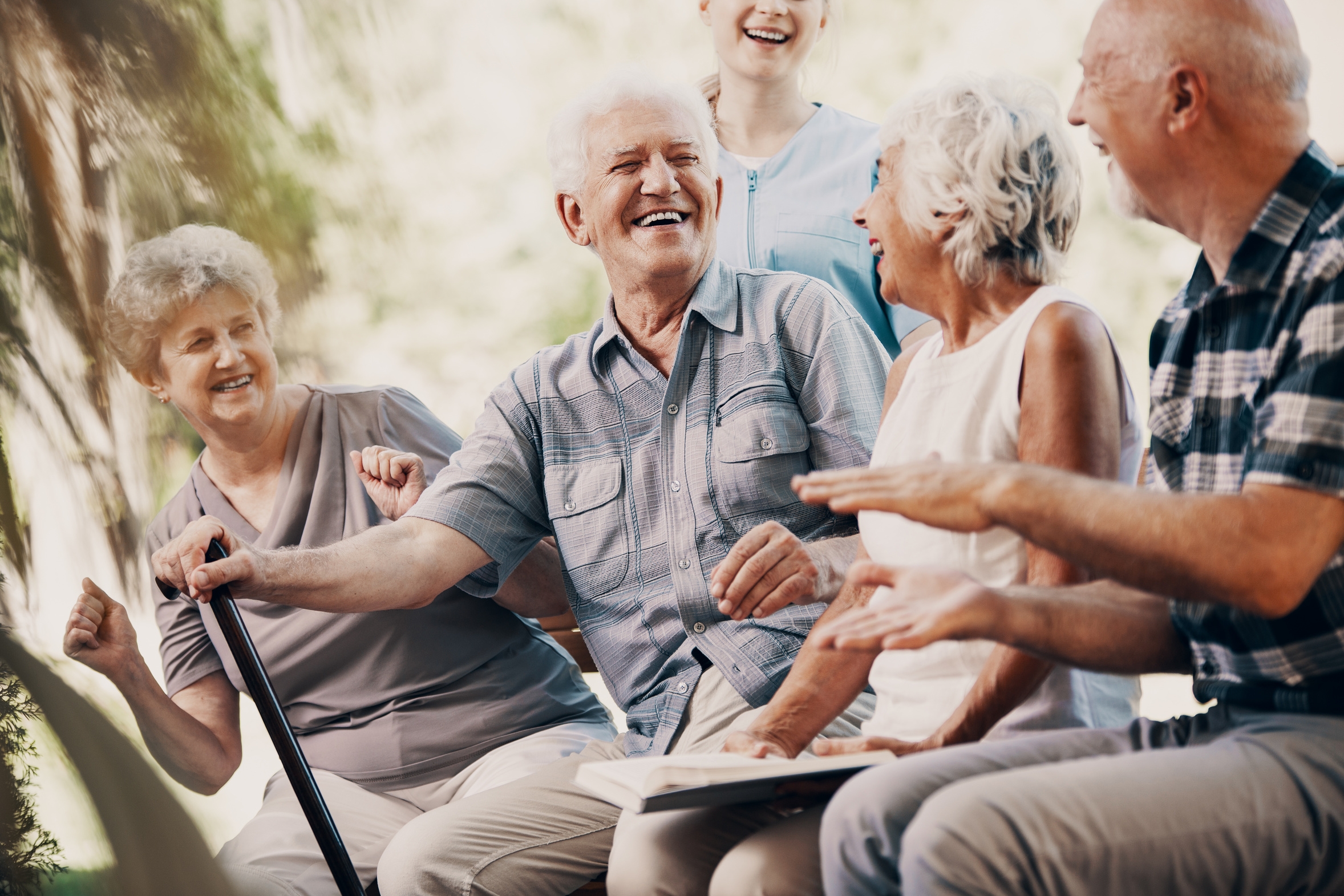 Happy elderly man with walking stick and smiling senior people relaxing in the garden Happy elderly man with walking stick and smiling senior people relaxing in the garden