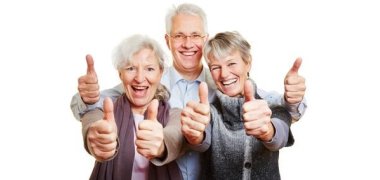 Drei Senioren halten glücklich Daumen hoch