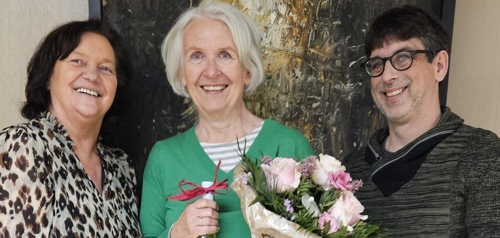 drei Personen, mittlere Person hat Geschenke in der Hand