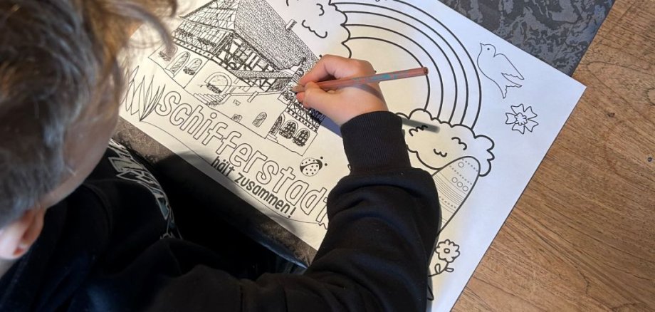 Kind am Tisch beim Bemalen eines Ausmalbildes