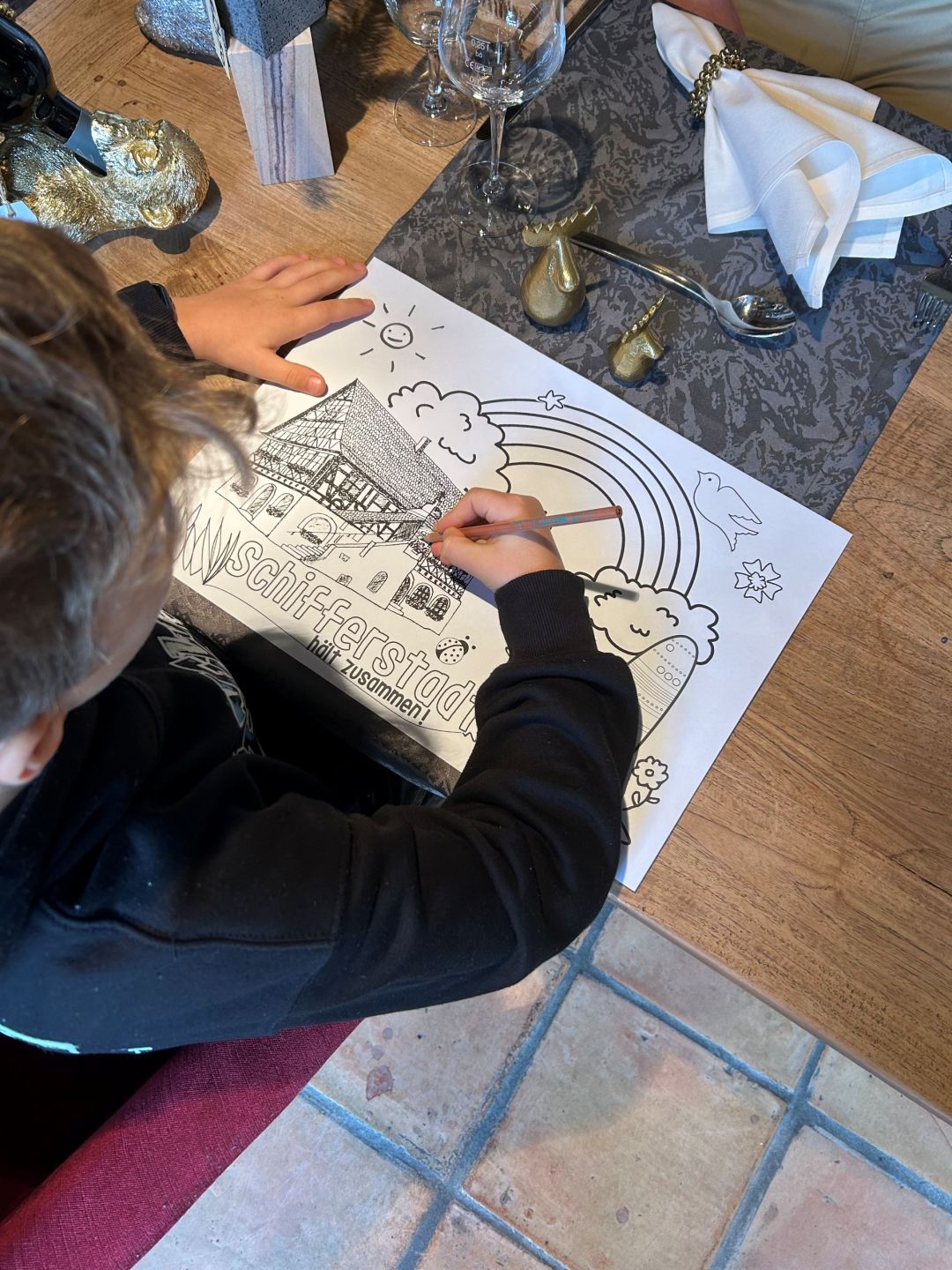 Kind am Tisch beim Bemalen eines Ausmalbildes