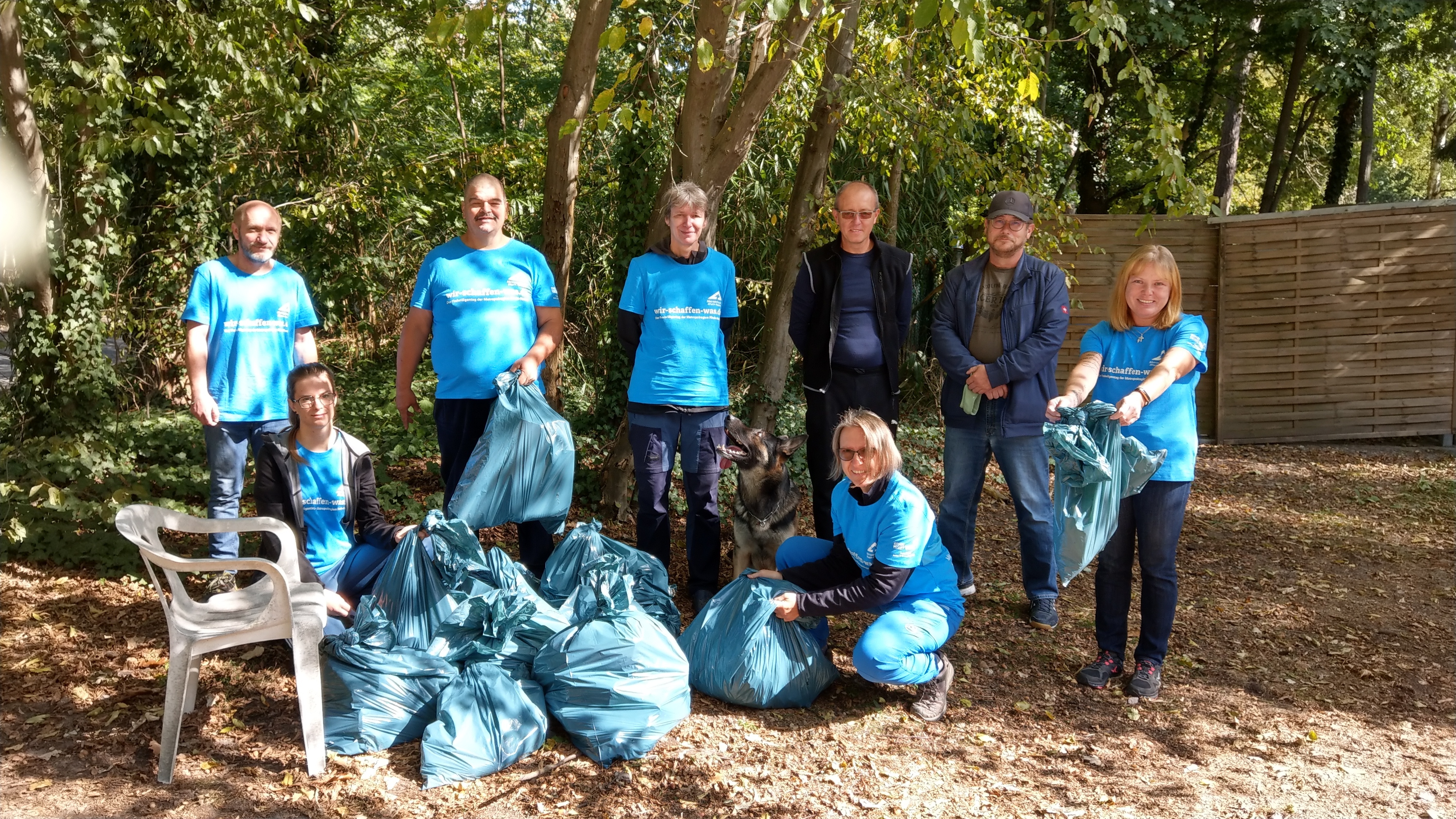 Helfer nach getaner Arbeit mit Müllsäcken und Werkzeug