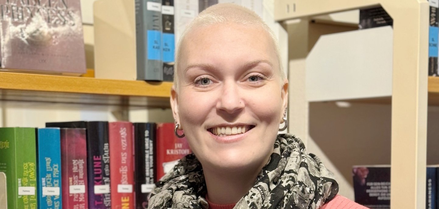 Frau mit kurzen hellblonden Haaren  vor Bücherregal