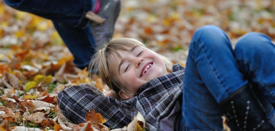 lachendes Kind im Herbstlaub