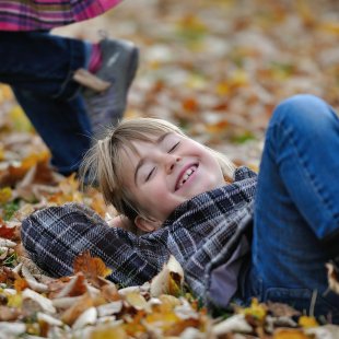 Kind spielt im Herbstlaub