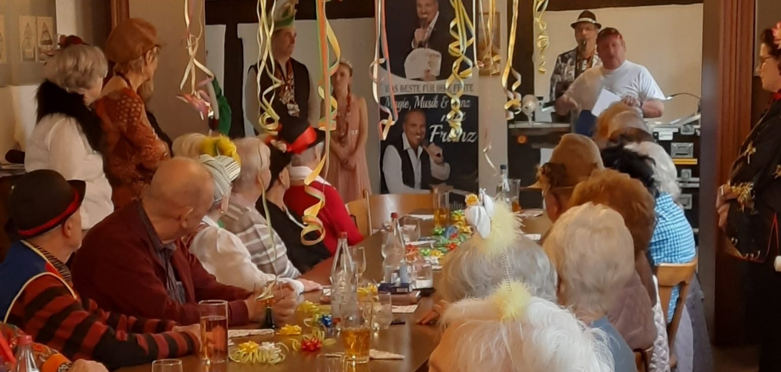 Frauen und Männer stehend und sitzend an geschmückten Tischen