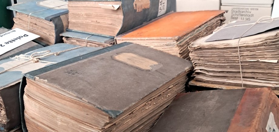 Alte Bücher im Vordergrund, im Hintergrund Rollregale