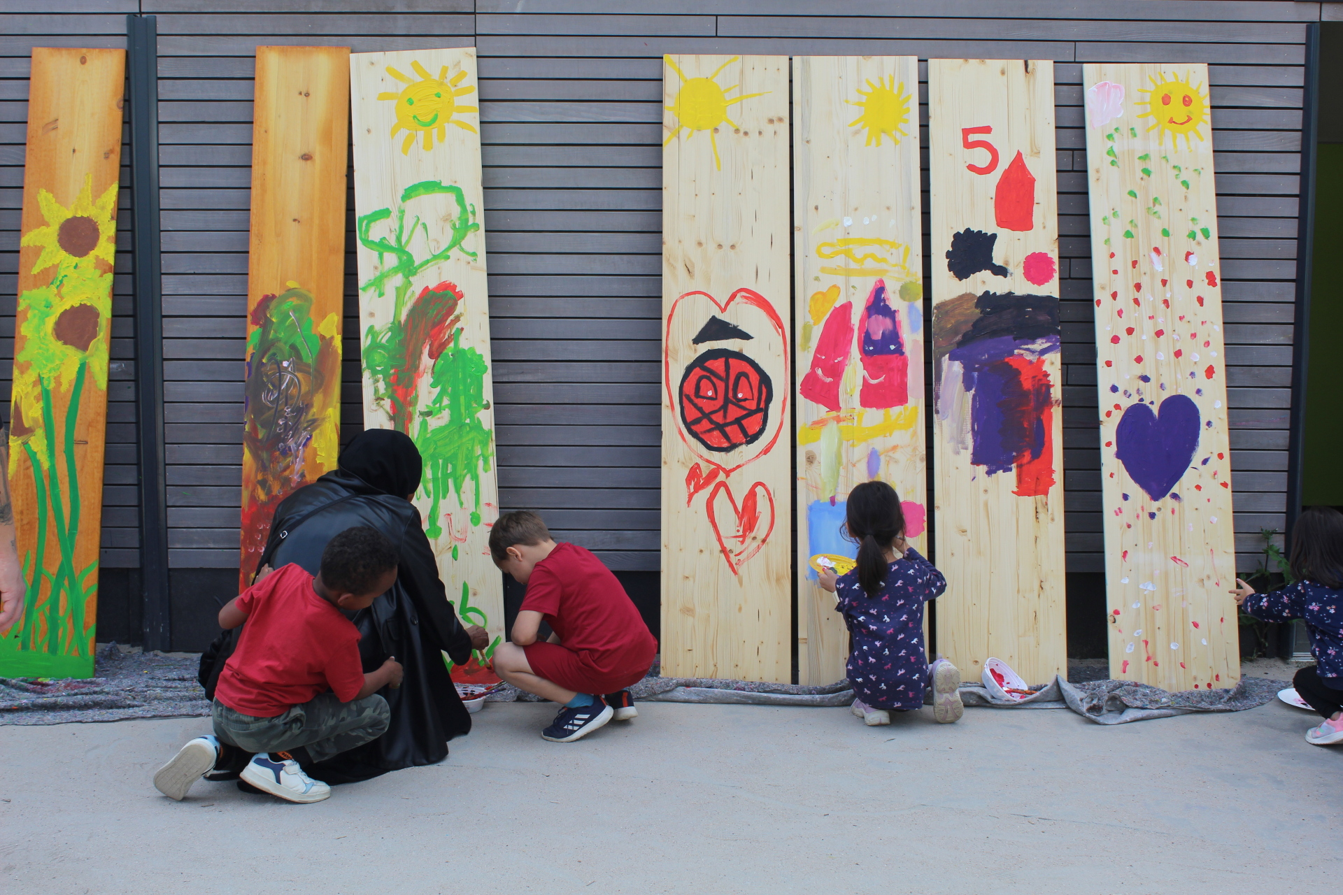 Kinder und Erwachsene beim Bemalen von Brettern
