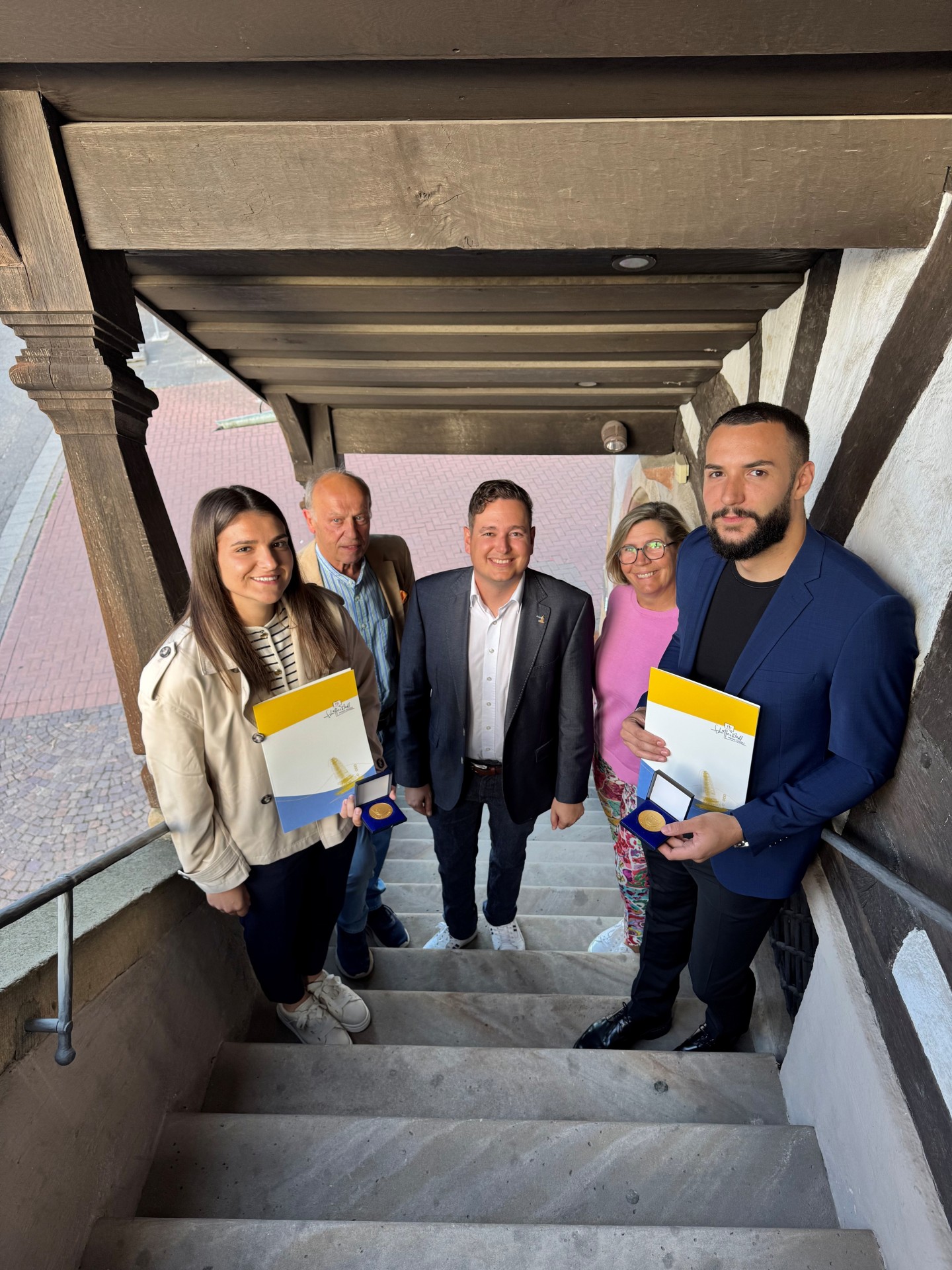 Menschen mit Urkunden in den Händen auf der Treppe des Alten Rathauses