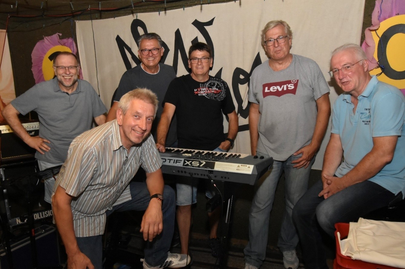 Die sieben Bandmitglieder gruppiert um ein Keyboard