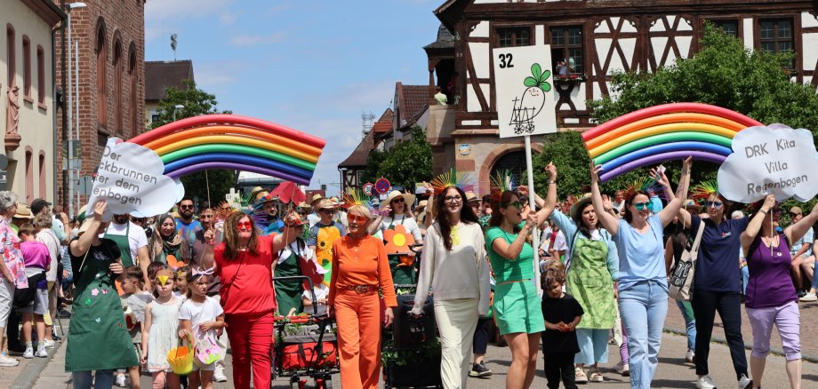 Fußgruppe in bunter Kleidung und selbst gebastelten Regenbögen