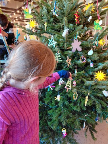 Mädchen, das beim Aufhängen von Weihnachtsbaumschmuck