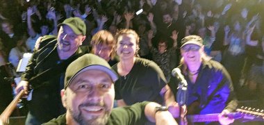 vier Männer und eine Frau mit Instrumenten in den Händen vor einer Menge Leute