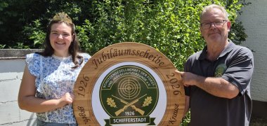 Frau und Mann mit Schützenvereinswappen in den Händen