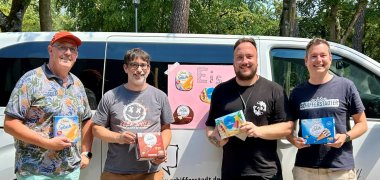 vier Männer vor einem Bus, der mit einem Schild "Eis" beklebt ist