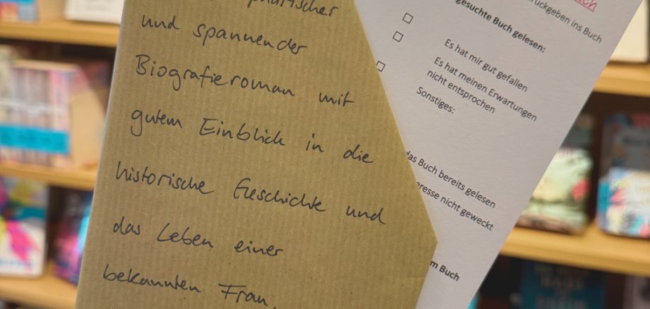 Beschrifteter Umschlag mit einem Fragebogen vor einem Bücherregal.