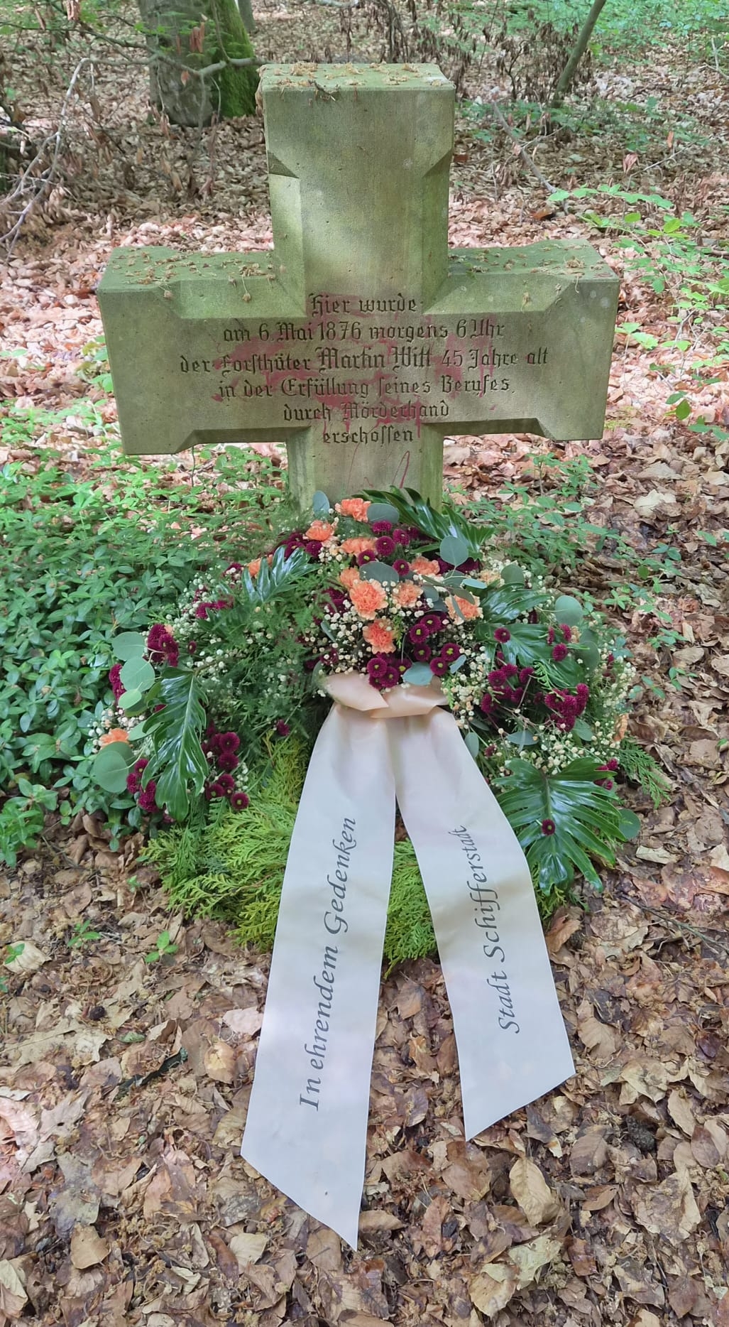 Gedenkkreuz mit Kranz im Wald