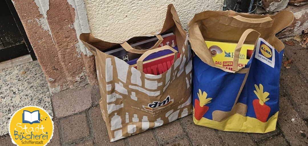 Tüten mit Büchern vor einem großen Kasten
