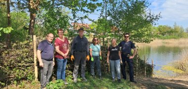 Menschen mit Werkzeug stehen vor einem Weiher